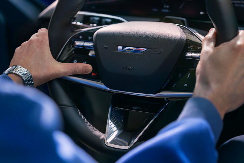Close-up of a Man About to Press the V-Button on the 2026 OPTIQ-V Steering Wheel | Fred Anderson Cadillac in Greer SC
