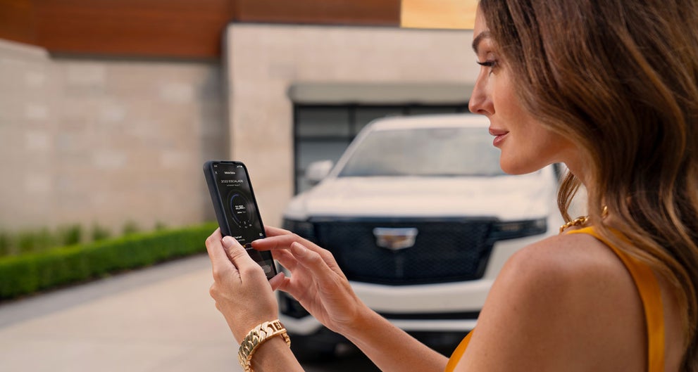 lady checking her mobile with a Cadillac vehicle background | Fred Anderson Cadillac in Greer SC